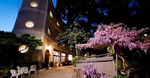 a building with a clock tower and a tree with purple flowers at Hotel Pensione Moderna in Bonassola