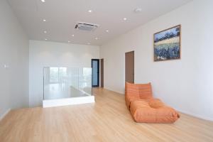 an orange couch in a white room with a painting at Haus 42 in Bangkok