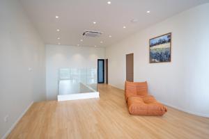an orange couch in a white room with a painting at Haus 42 in Bangkok