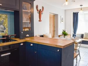 a kitchen with blue cabinets and a wooden counter top at White Horses - Uk42776 in Newborough +10 photos