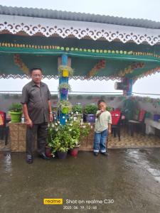 a man and a young boy standing in front of a flower shop at Kotheybari homestay in Pakhyong