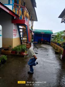 a young boy running in the rain in front of a store at Kotheybari homestay in Pakhyong