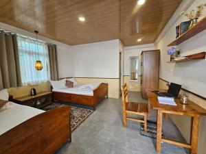 a bedroom with a bed and a desk with a laptop at Kotheybari homestay in Pakhyong