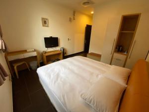 a bedroom with a white bed and a desk with a computer at 富喜民宿二館 in Nangan