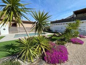 a group of palm trees and purple flowers in front of a building at Casa Rural Maño in Deltebre
