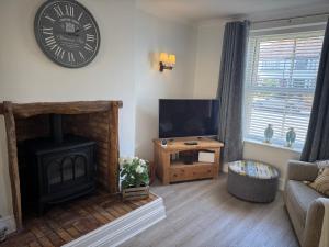 a living room with a fireplace and a clock on the wall at The Hideaway in Llandudno