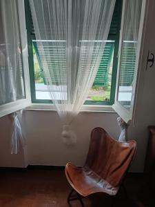 a chair in front of a window with curtains at Casa JEANMARC in Moneglia