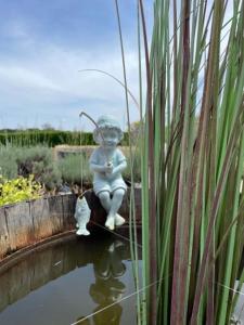a statue of a little boy sitting on a fish pond at Maison M in Surin