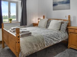 a bedroom with a wooden bed and a window at New House Farm - Ukc6912 in Leck +11 photos