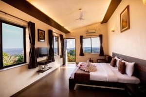 a bedroom with a bed with windows and a television at Cloud 9 Hills Resort in Lonavala