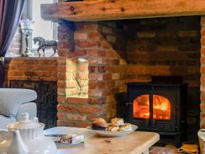 a brick fireplace with a plate of pastries on a table at Honey Pots in Foulden