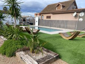 a backyard with a swimming pool and chairs and a house at Casa Rural MESTRE in Deltebre