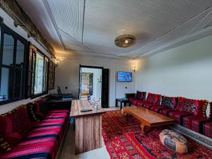a living room with red couches and a wooden table at Tonaroz House in Imlil