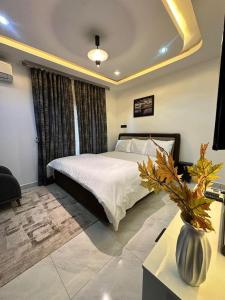 a bedroom with a bed and a vase on a table at SKYBUILT APARTMENTs in Abuja