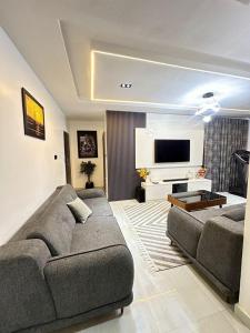 a living room with a couch and a flat screen tv at SKYBUILT APARTMENTs in Abuja