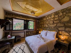 a bedroom with a large bed with a stone wall at Tonaroz House in Imlil