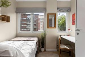 a bedroom with a bed and a desk and two windows at 5BR 2Bath Frogner - Parking - Vigelandsparken in Oslo