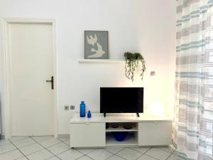 a white living room with a television on a white cabinet at Astros by the sea in Paralio Astros