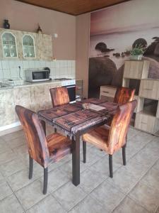 a kitchen with a wooden table with chairs and a counter at Juci Home Apartman in Vonyarcvashegy