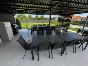 a black dining table and chairs under a pavilion at Laura Apartmanház in Mórahalom