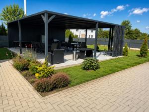a black pavilion with a picnic table in a garden at Laura Apartmanház in Mórahalom