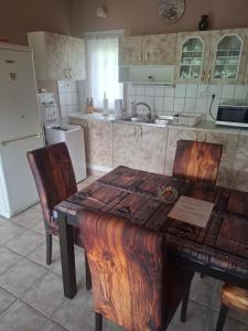 a kitchen with a wooden table and chairs and a refrigerator at Juci Home Apartman in Vonyarcvashegy