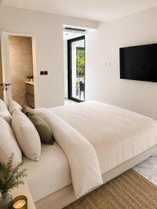 a white bedroom with a large bed and a flat screen tv at Contemporary villa between Paris and Disneyland in Champs-sur-Marne +9 photos