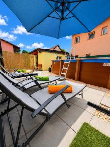 a group of chairs sitting on a patio under an umbrella at Apartman Josip with Pool in Gospić