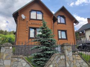 a wooden house with a tree in front of it at Вілла Олекси in Skhidnitsa