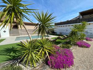 a group of palm trees and purple flowers in front of a building at Casa rural Mestre in Deltebre