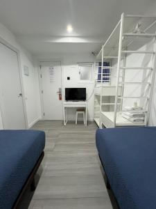 a room with two beds and a desk with a tv at Hostel Hock Residences in Hospitalet de Llobregat