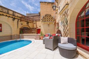 a backyard with a swimming pool and chairs and a building at Ta' Kullarina Farmhouse in Żebbuġ