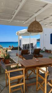 a wooden table and chairs with an umbrella and the ocean at Petradi Residence Sifnos in Platis Gialos