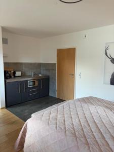 a bedroom with a large bed and a kitchen at Ferienwohnung Alpensteinbock in Nesselwang +8 photos