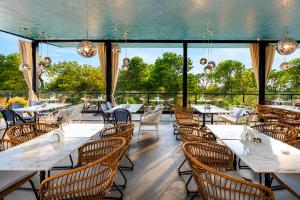 a restaurant with tables and chairs and large windows at Kobuleti Garden Inn in Kobuleti