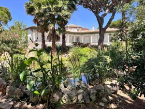 a large white house with palm trees and a garden at Villa com piscinas - Quintinha do Lago in Quarteira