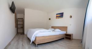 a bedroom with a bed with white sheets and a television at Casa Ana Maria in Vama Veche