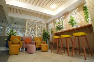 a lobby with chairs and a bar with yellow stools at Aurelia INN - JP Nagar in Bangalore