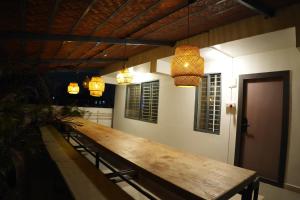 a long wooden table in a room with lights at Aurelia INN - JP Nagar in Bangalore