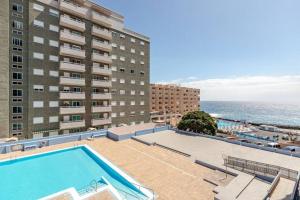 a swimming pool next to a building and the ocean at The beach nest in Candelaria
