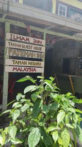 a sign in front of a building with a plant at Ilham inn in Jerantut