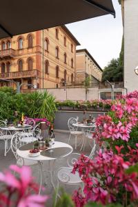 a patio with tables and chairs and pink flowers at Sangallo Palace in Perugia