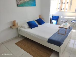 a bedroom with a bed with blue pillows and a table at The beach nest in Candelaria +19 photos