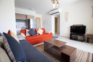 a living room with an orange couch and a tv at Marina Marassi in El Alamein