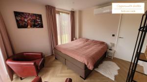 a small bedroom with a bed and a chair at De Bosanemoon with Sauna | 6 persons in Gasselte