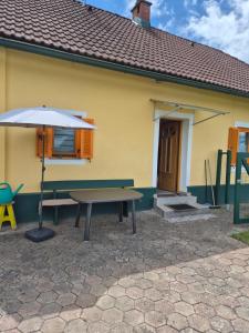 a table and an umbrella in front of a yellow house at Chalet an der Sonne nahe Klopeiner See und Petzen Bergbahn in Sankt Stefan