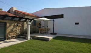 a patio with a table and an umbrella in a yard at Casa rural Villa Quintans in Soutullo