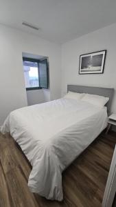 a large white bed in a white bedroom with a window at Casa rural Villa Quintans in Soutullo