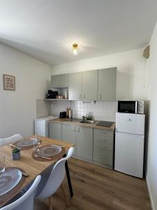a kitchen with a table and a white refrigerator at Le Nid de la Mayenne in Mayenne
