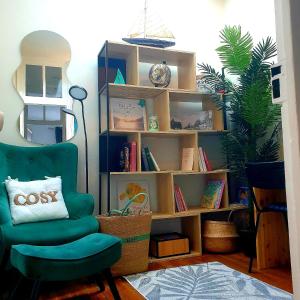 a living room with a green chair and a book shelf at La Villa Turquoise in Le Tréport